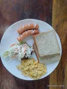 a white plate of food with sausage and a sandwich at Cacha Hotel in Bangkok