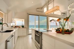 a kitchen with white cabinets and a view of the ocean at Luxe Oceanfront Waianae Home with Lanai - Near Beach in Waianae