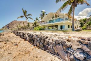 a house on the beach with a rock wall at Luxe Oceanfront Waianae Home with Lanai - Near Beach in Waianae