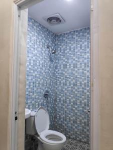 a bathroom with a toilet and a blue tiled wall at The Galton Hotel in Baubau