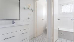 a white bathroom with a sink and a mirror at Beachcomber in Old Bar
