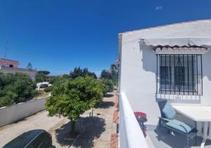 Un balcón con una mesa, una silla y un árbol en Private room ensuite with private balcony, en Chiclana de la Frontera