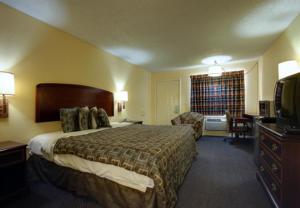 Americas Best Value Inn Comanche في Comanche: فندق غرفه بسرير وصاله