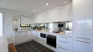 a large white kitchen with white cabinets and appliances at Sea Breeze in Old Bar