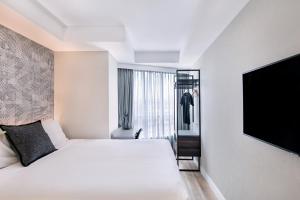 a hotel room with a bed and a flat screen tv at Kith Hotel Darling Harbour in Sydney