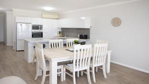 a kitchen and dining room with a wooden table and chairs at Apartment 14 - The Meridian in Old Bar