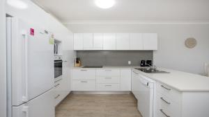 a white kitchen with a sink and a refrigerator at Apartment 14 - The Meridian in Old Bar
