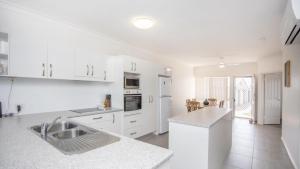 a white kitchen with a sink and a counter at Apartment 19 - The Meridian in Old Bar