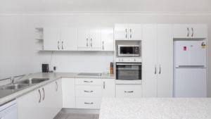 a white kitchen with white cabinets and appliances at Apartment 19 - The Meridian in Old Bar