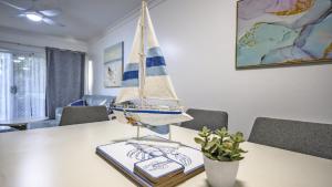 a toy sailboat on a table with a book at Apartment 27 - The Meridian in Old Bar