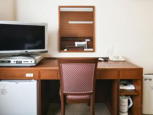 - un bureau avec un ordinateur, une télévision et une chaise dans l'établissement Vessel Hotel Fukuoka Kaizuka, à Fukuoka