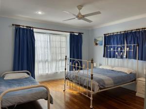 zwei Betten in einem Schlafzimmer mit blauen Vorhängen in der Unterkunft Cooloola Cottage Rainbow Beach in Rainbow Beach