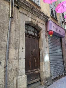 um edifício antigo com uma porta e um guarda-chuva rosa em Le Studio Cosy, centre historique, wifi, neuf em Grasse