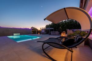 a chair sitting on a patio next to a swimming pool at Kuća za odmor Dora in Benkovac