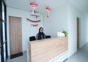 a woman sitting at a counter in an office at OFO Kost Premium Syariah Kampung Inggris Pare in Pare