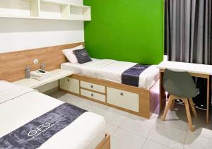 a bedroom with two beds and a green wall at OFO Kost Premium Syariah Kampung Inggris Pare in Pare
