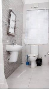 a bathroom with a toilet and a sink and a window at BTT Homes in Lekki