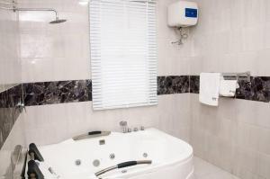 a white bathroom with a tub and a window at BTT Homes in Lekki