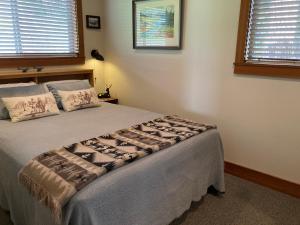 a bedroom with a bed and two windows at Hideaway Ranch in Bonners Ferry