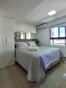 a bedroom with a bed with white sheets and a window at Apart-hotel 36m² Varanda Vista Mar no Cabo Branco in João Pessoa