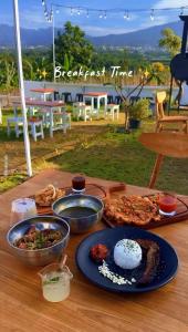 a wooden table with plates of food on it at Crazy Steak Resort Glamping Villa in Batu