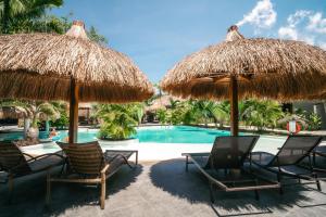a group of chairs and umbrellas next to a swimming pool at Secret paradise moalboal in Moalboal