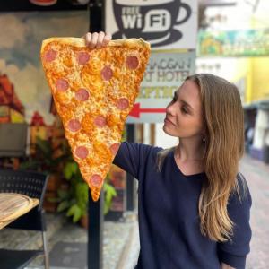 a woman holding up a large slice of pizza at Khaosan Art Hotel - SHA Plus Certified in Bangkok