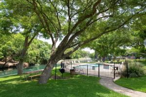 un parque con un árbol y una valla y una piscina en River Hippie RRC A302 en New Braunfels
