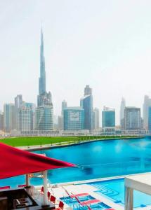 a swimming pool with a city skyline in the background at Canal Central Hotel Business Bay in Dubai