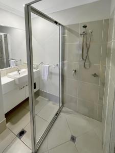uma casa de banho com um chuveiro e um lavatório. em Direct Collective - Villas on Rivergum em Emerald