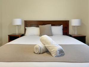 een opgerolde handdoek bovenop een bed bij Direct Collective - Villas on Rivergum in Emerald
