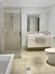 a bathroom with a shower and two sinks and a toilet at Direct Collective - Villas on Rivergum in Emerald