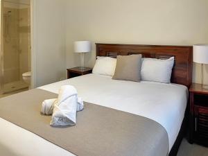 een slaapkamer met een groot wit bed en handdoeken bij Direct Collective - Villas on Rivergum in Emerald