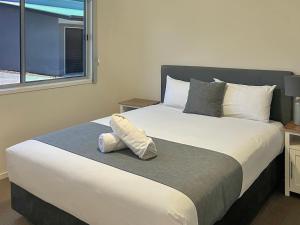 a bedroom with a large white bed with a window at Direct Collective - Villas on Rivergum in Emerald