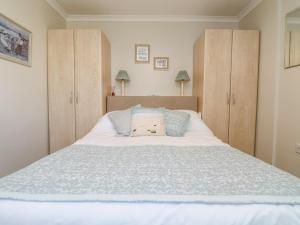 - une chambre avec un grand lit blanc et des placards en bois dans l'établissement Bre An Mor, à Germoe