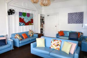 a living room with blue couches and colorful pillows at Original Backpackers in Sydney