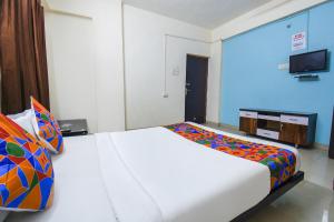 a bedroom with a white bed with a colorful blanket at FabExpress Shri Krishna in Pune