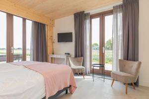 um quarto com uma cama, uma secretária e cadeiras em De Groene Bollenschuur em Hillegom