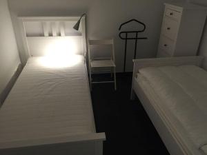 ein Schlafzimmer mit einem weißen Bett und einem Stuhl in der Unterkunft New building, first occupancy, Niendorf enclosure in Hamburg