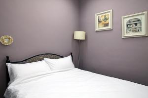 a bedroom with a bed with white sheets and a lamp at Dora's World in Jian