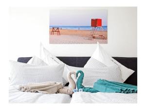 a white bed with a stuffed animal on it next to the beach at Old Printing House Holiday Apartment Gutenberg in Norderney