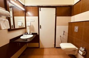 a bathroom with a toilet and a sink and a door at Holiday Valley Hotels And Resorts in Denkanikottai