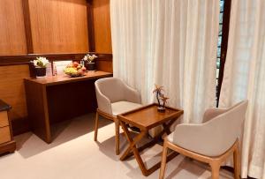 Zimmer mit einem Schreibtisch, 2 Stühlen und einem Tisch in der Unterkunft Holiday Valley Hotels And Resorts in Denkanikottai