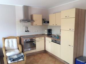uma cozinha com armários brancos, uma cadeira e um lavatório. em Boddensurfer 2a Comfortable holiday residence em Pruchten