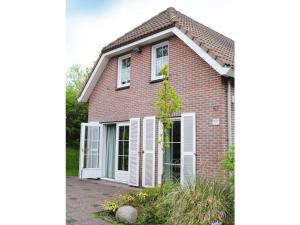a brick house with white windows and a tree at Huijsmansverhuur Type Premium de Luxe in Ouddorp