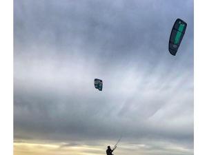 Eine Person fliegt zwei Drachen in den Himmel in der Unterkunft Chalet IJsselmeerstrand First row in Enkhuizen