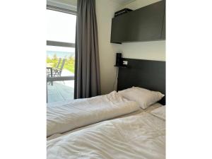 een slaapkamer met een bed met witte lakens en een raam bij Chalet IJsselmeerstrand First row in Enkhuizen