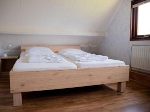 a wooden bed with two pillows on it in a room at Huijsmans Verhuur Type Deluxe Zuiderdiep 11 in Ouddorp