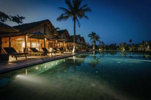 a resort swimming pool at night with palm trees at Zannier Phum Baitang in Siem Reap