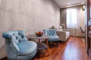 sala de estar con sillas azules y mesa en Arch Apart Hotel en Ereván